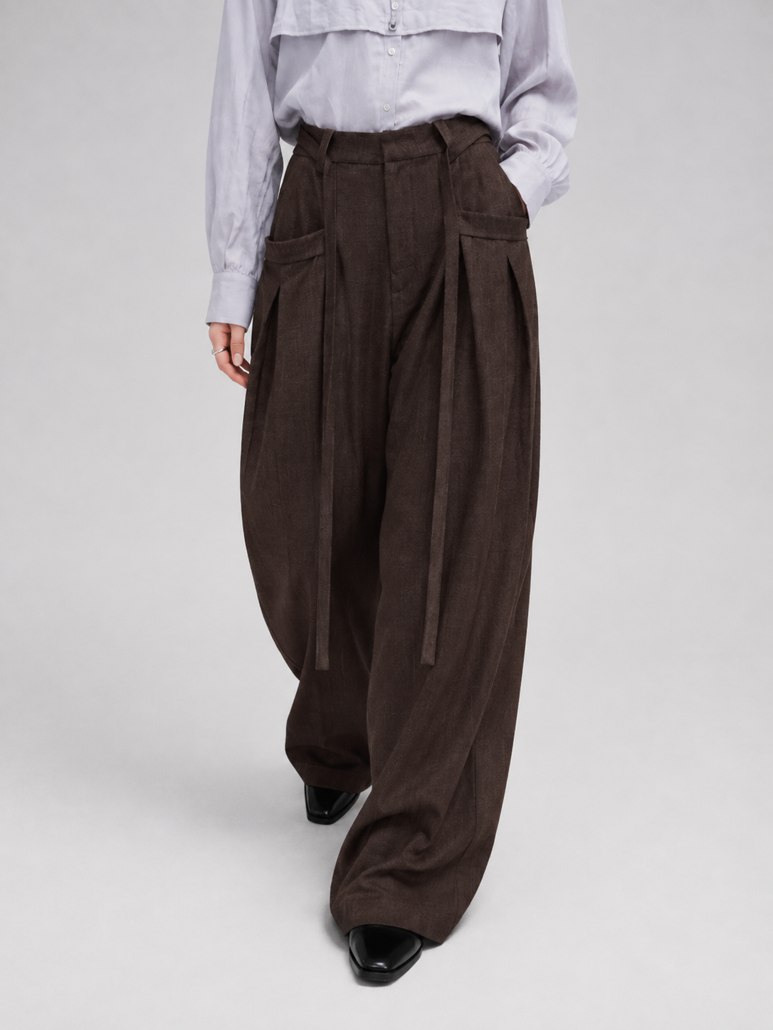 Dark brown wide-leg trousers with front pleats and a draped waistband